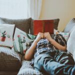 A person laying on the sofa reading a book